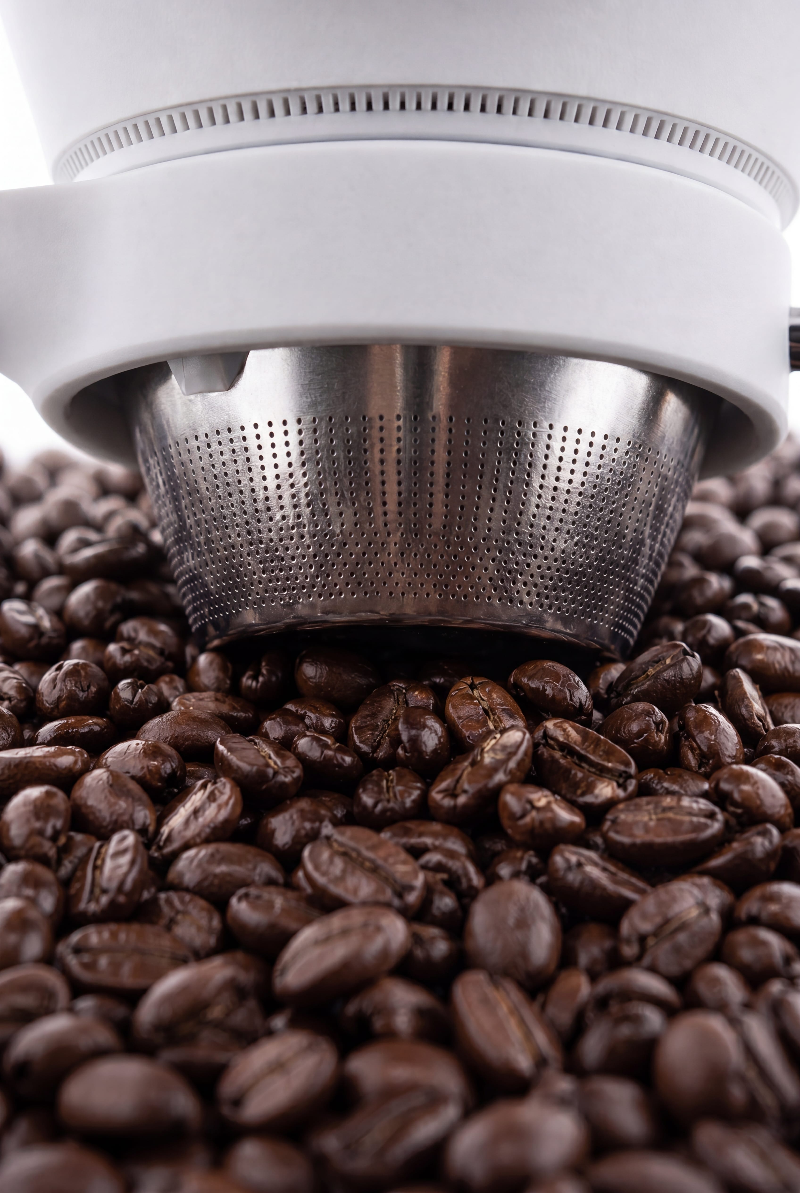 Macro view of the CoolDrip stainless steel filter resting on coffee beans