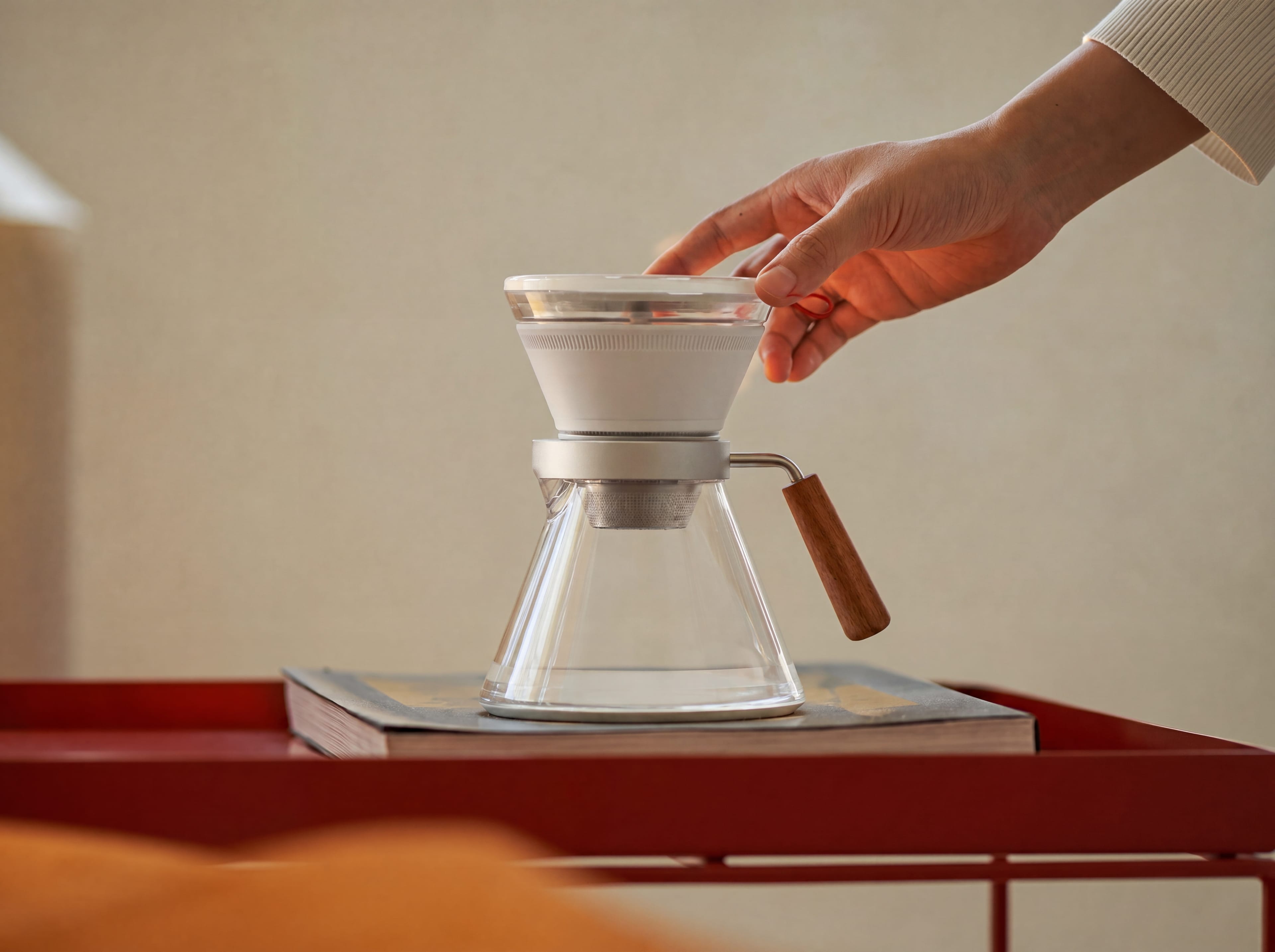 A hand adjusting the CoolDrip lid on a warm tabletop